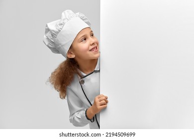 Cooking, Culinary And Profession Concept - Happy Smiling Little Girl In Chef's Toque And Jacket With White Board Over Grey Background