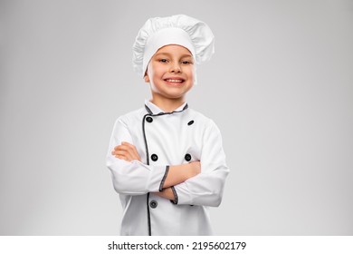 Cooking, Culinary And Profession Concept - Happy Smiling Little Boy In Chef's Toque And Jacket Over Grey Background