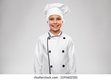 Cooking, Culinary And Profession Concept - Happy Smiling Little Boy In Chef's Toque And Jacket Over Grey Background