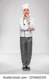 Cooking, Culinary And Profession Concept - Happy Smiling Little Boy In Chef's Toque And Jacket Over Grey Background