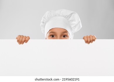 Cooking, Culinary And Profession Concept - Little Boy In Chef's Toque And Jacket Peeking Out From Behind White Board Over Grey Background