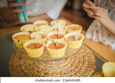 Cooking Cupcakes With Kids, Kid Decorating Cupcakes On A Glass Plate On A Table