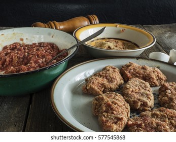 Cooking of cutlets.  Lamb mince in metallic bowl, breadcrumbs and cutlets in breadcrumbs on a plate on old weathered wooden table