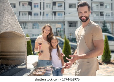 Cooking. Dad Grilling Meat While His Daughter And Wife Standing Near