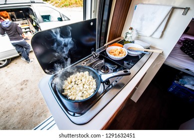Cooking dinner or lunch in campervan, motorhome or RV. Preparing chicken  in a pan in camper van when traveling with RV, motor home caravan or motorvan. Vanlife or van life lifestyle on the road.