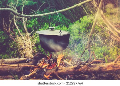 Cooking in field conditions, boiling pot at the campfire on picnic. Filtered image:cross processed vintage effect. 