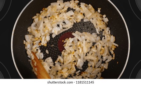 Cooking Food Concept. The Cook Is Cooking The Onion In A Frying Pan. Kind Of The First Perspective, The Point Of View Of The Chef Person. Glass-ceramic Radiant Hob As Background.