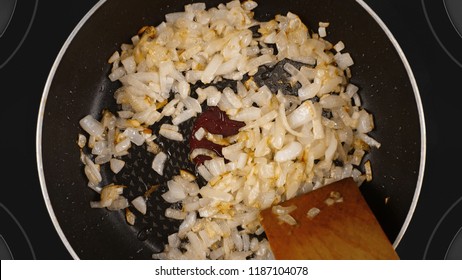 Cooking Food Concept. The Cook Is Cooking The Onion In A Frying Pan. Kind Of The First Perspective, The Point Of View Of The Chef Person. Glass-ceramic Radiant Hob As Background.