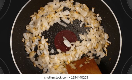 Cooking Food Concept. The Cook Is Cooking The Onion In A Frying Pan. Kind Of The First Perspective, The Point Of View Of The Chef Person. Glass-ceramic Radiant Hob As Background.