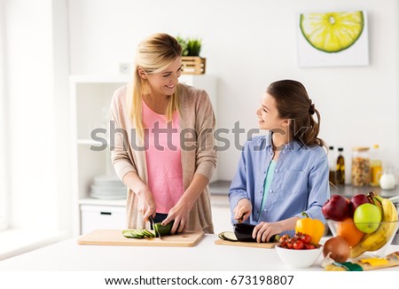 Teenage girl helping to water the flowers growing in flower pot, pouring water from green watering can, working in backyard at sunset. Candid people, real moments, authentic situations