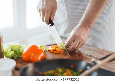 Cooking, Food And Home Concept - Close Up Of Male Hand Cutting Pepper On Cutting Board At Home