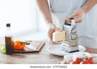 Cooking, Food And Home Concept - Close Up Of Male Hands Grating Cheese