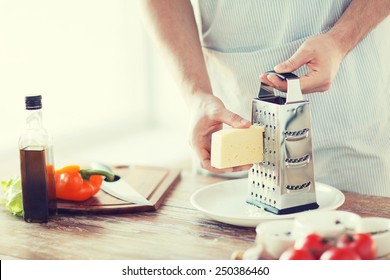 cooking, food and home concept - close up of male hands grating cheese - Powered by Shutterstock