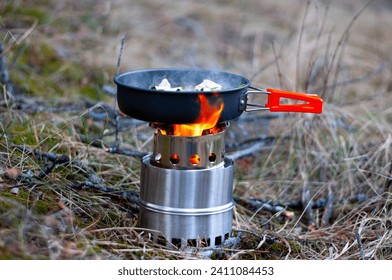 Cooking food in a pan on a portable camping stove in the woods.  - Powered by Shutterstock