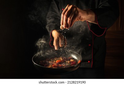 Cocinando verduras frescas. El chef pone sal en una sartén caliente al vapor. Gran idea gastronómica para un hotel con espacio publicitario.