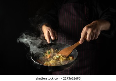 Cooking fresh vegetables and noodles. The cook flips food in a hot frying pan. Thai street food - Shutterstock ID 2193682693