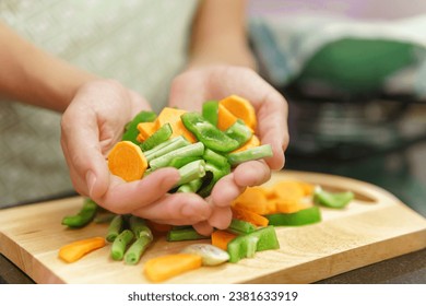 Cooking fresh vegetables: orange carrot, green bell pepper, okra and green beans. Colorful view of pieces of vegetables on a cutting board in a kitchen. Healthy product of organic farming. - Powered by Shutterstock