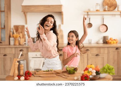 Cooking Fun. Mommy And Daughter Kid Fooling While Preparing Dinner Together, Dancing And Singing In Modern Kitchen At Home, Making Salad And Fresh Vegetable Meals. Family Nutrition, Recipes - Powered by Shutterstock