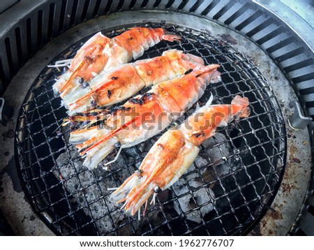 Cooking grilled shrimp with oven charcoal grill by grilled on steel grating. Below is the charcoal that is very hot.