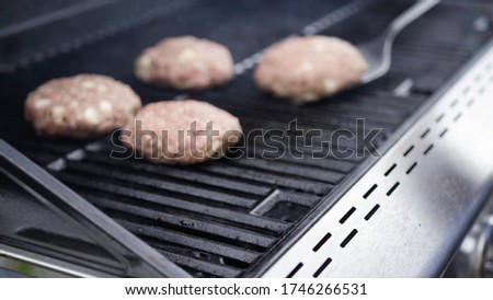 Cooking hamburger beef patties on a gas grill.