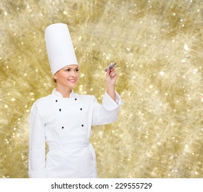 Cooking, Holidays, Advertisement And People Concept - Smiling Female Chef, Cook Or Baker With Marker Writing Something On Virtual Screen Over Yellow Lights Background