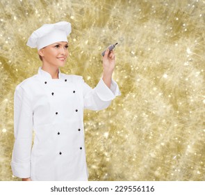 Cooking, Holidays, Advertisement And People Concept - Smiling Female Chef, Cook Or Baker With Marker Writing Something On Virtual Screen Over Yellow Lights Background