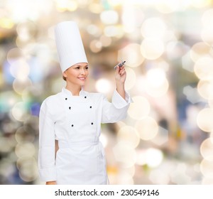 Cooking, Holidays, Advertisement And People Concept - Smiling Female Chef, Cook Or Baker With Marker Writing Something On Virtual Screen Over Lights Background