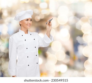 Cooking, Holidays, Advertisement And People Concept - Smiling Female Chef, Cook Or Baker With Marker Writing Something On Virtual Screen Over Lights Background