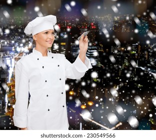 Cooking, Holidays, Advertisement And People Concept - Smiling Female Chef, Cook Or Baker With Marker Writing Something On Virtual Screen Over Snowy Night City Background