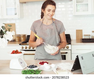 Cooking, Home Business, Freelance, People and Hobbies concept: Young woman pastry chef mixes the cream and looks at the recipe on the tablet. Modern cuisine. - Powered by Shutterstock