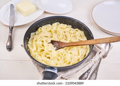 Cooking Homemade Alfredo Pasta - Hot Fettuccine In A Pan With Butter And Cheese Sauce With A Wooden Spoon