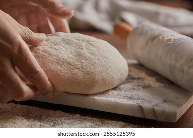 Cooking homemade bread. Sieving flour over raw bread dough rolled with rolling pin on marble board, dark background, selective focus. Baker hands on dough. - Powered by Shutterstock