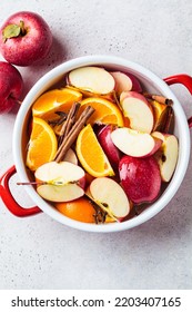 Cooking Homemade Hot Cider From Apples And Oranges With Spices In A Red Saucepan, Top View. Autumn Or Winter Warming Drink.