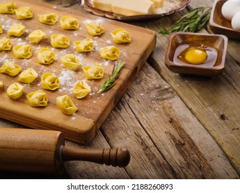 Cooking Homemade Ravioli, Dumplings. Small Ravioli, Dumplings On A Cutting Board, Kitchen Utensils On A Wooden Background. There Are No People In The Photo. There Is Free Space To Insert.