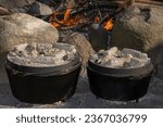 Cooking with hot charcoals atop of two cast iron dutch ovens.