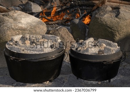 Cooking with hot charcoals atop of two cast iron dutch ovens.