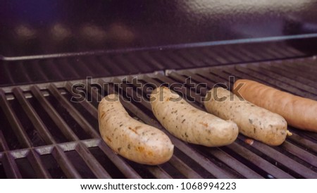 Cooking hot dogs and bratwurst on outdoor gas grill in the Summer.