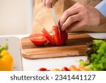 Cooking image of a young man cutting tomatoes