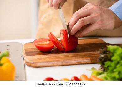 Cooking image of a young man cutting tomatoes - Powered by Shutterstock