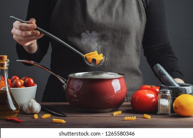 Cooking Italian Pasta In A Pot In The Kitchen, Chef Preparing Food, Meal. Woman Cook Pulls Out Of The Pan Ready-made Pasta Fusilli