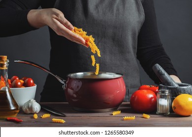Cooking italian pasta in a pot in the kitchen, Chef preparing food, meal. The woman-the cook throws into the pot the pasta fusilli - Shutterstock ID 1265580349