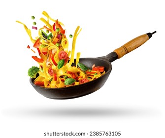 Cooking Italian pasta with vegetables flying over a hot frying pan isolated in white. The concept of food levitation