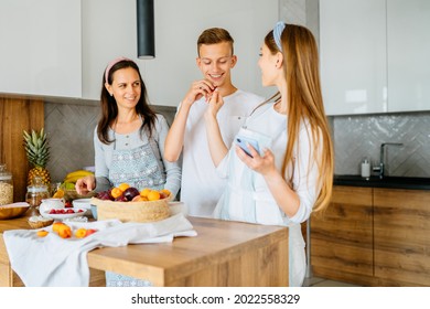 Cooking Lesson. Happy Mom Teaching Adult Daughter And Teen Son Prepare Healthy Nutrition, Caucasian Mother With Two Grown Children Talking Smiling Engaged In Useful Activity At Kitchen.