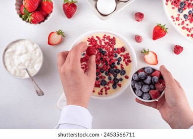 Cooking making baked yogurt healthy dessert. Woman hand cooking oven baked greek yogurt dessert with fresh frozen berries, on white kitchen table, with ingredients, top view - Powered by Shutterstock