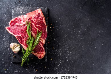 Cooking meat background. Raw aged beef t-bone steak, with spices and herbs for cooking on a gray table background top view - Powered by Shutterstock