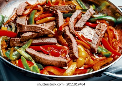 Cooking Mexican top round steak fajitas in giant pan on stovetop