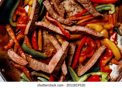 Cooking Mexican top round steak fajitas in giant pan on stovetop