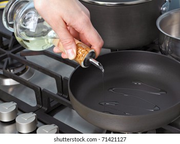 Cooking Oil Being Pourred From A Glass Bottle Into A Pan.