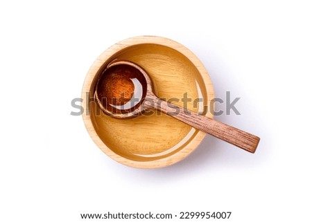 Cooking oil or sugar syrup in wooden bowl with spoon isolated on white background with clipping path. Top view, flat lay.