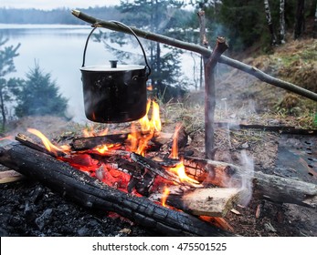 Cooking on the fire for a camping trip. Pot over a fire outdoors. The romance of the wild tourism and food in camp. Backpacking on the nature at sunset. 